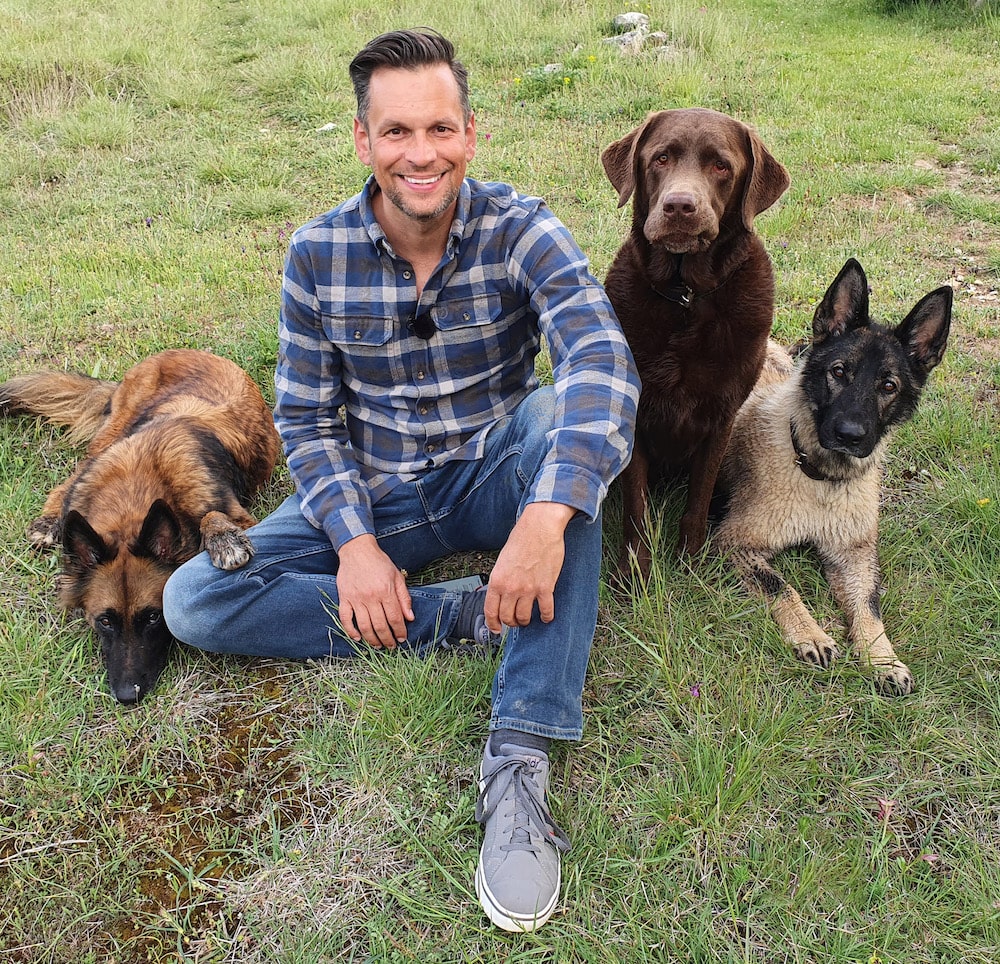 Dog University: Daniel Joeres sitzt auf der Wiese mit 3 Hunden